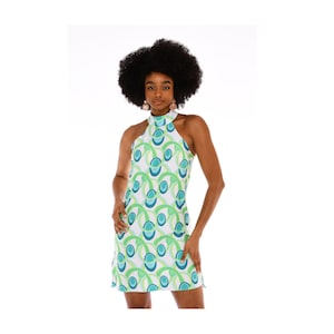 May include: A white halter dress with a green and blue geometric pattern. The dress has a high neckline and a sleeveless design.