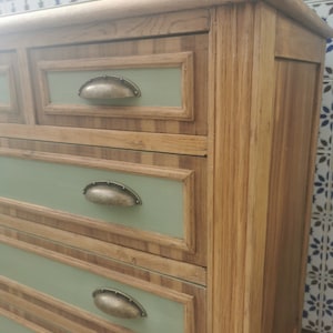 May include: A wooden dresser with four drawers. The drawers have a light green painted front with a dark wood trim. Each drawer has a metal knob.