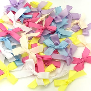 May include: A collection of pastel-coloured satin ribbon bows. The bows are in shades of pink, blue, yellow, and white. They are perfect for adding a touch of elegance to gifts, crafts, or home decor.