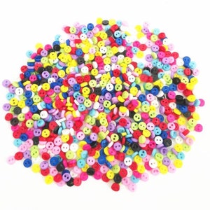 May include: A large pile of colourful two-hole buttons. The buttons are small and come in a variety of colours, including red, yellow, blue, green, pink, purple, and white.