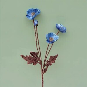 Puede incluir: Un ramo de tres flores de amapola artificiales azules con tallos y hojas marrones.