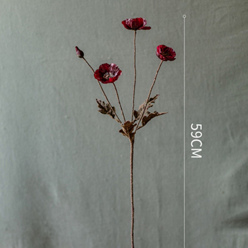 Puede incluir: Un ramo de tres flores de amapola rojas artificiales con tallos y hojas marrones. Las flores miden 59 cm de alto.