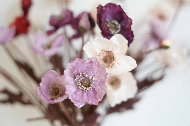 Puede incluir: Un ramo de delicadas flores artificiales con p&eacute;talos rosas, blancos y morados. Las flores tienen un aspecto realista y est&aacute;n dispuestas en un racimo.