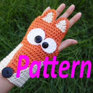 May include: Crocheted orange and white fox fingerless gloves with black button accents and large white eyes. The gloves are on a hand with the word "Pattern" in pink letters below the hand.