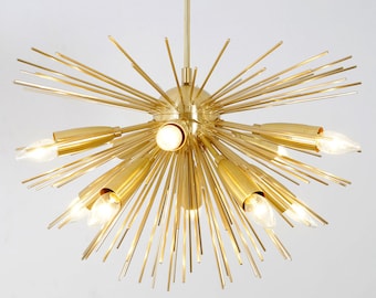 May include: A gold-toned, starburst-shaped chandelier with multiple light bulbs. The chandelier has a modern design and is made of metal.
