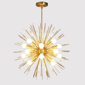 May include: A gold-toned, modern chandelier with a starburst design. The chandelier has multiple light bulbs and long, thin arms that extend outward.