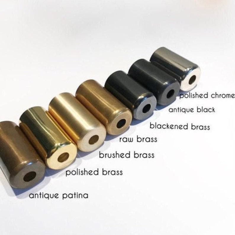 May include: A close-up of eight metal lamp finials in different finishes, including polished chrome, antique black, blackened brass, raw brass, brushed brass, polished brass, and antique patina.