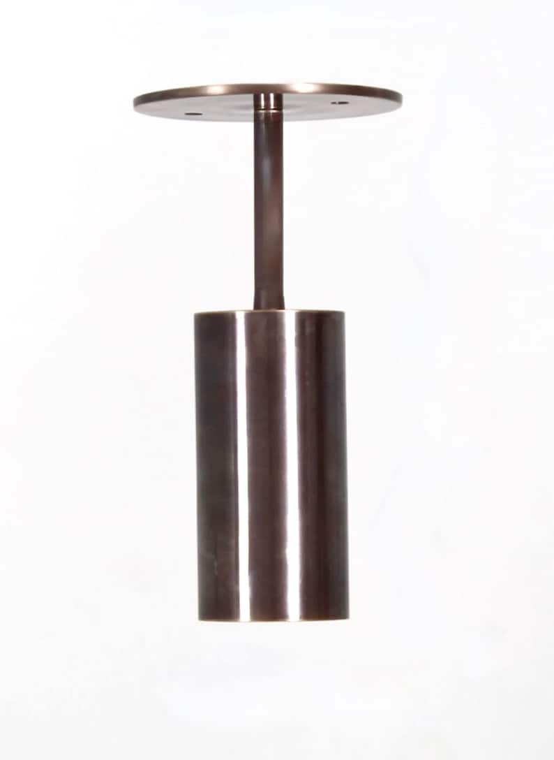 May include: A brushed bronze pendant light fixture with a cylindrical shade and a circular canopy.