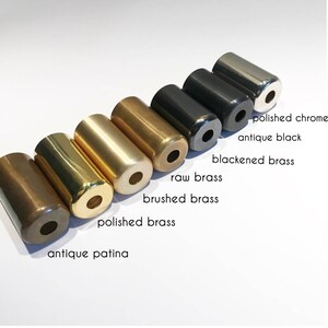 Puede incluir: Primer plano de ocho tapas de cilindro de metal en diferentes acabados: p&aacute;tina antigua, lat&oacute;n pulido, lat&oacute;n cepillado, lat&oacute;n en bruto, lat&oacute;n ennegrecido, negro antiguo y cromo pulido.