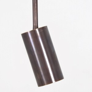 May include: A brushed bronze cylindrical pendant light fixture with a round ceiling mount.