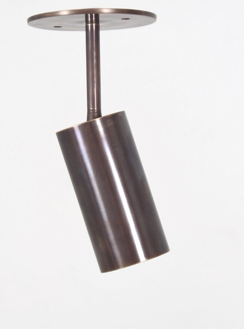 May include: A brushed bronze cylindrical pendant light fixture with a round ceiling mount.