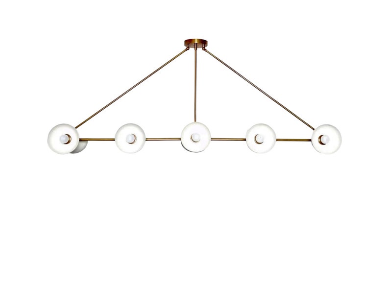 May include: A modern gold-toned chandelier with six white glass globe lights. The lights are arranged in a linear pattern with two arms extending from the center.