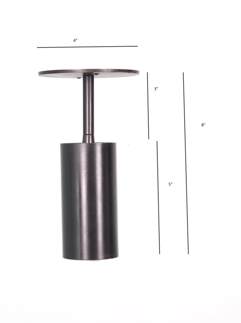 May include: A black metal ceiling light fixture with a cylindrical shade and a round canopy. The fixture is 8 inches tall, 4 inches wide, and 3 inches deep.