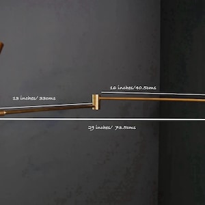 Puede incluir: Una l&aacute;mpara de pared dorada con una pantalla en forma de cono y un brazo ajustable. La l&aacute;mpara mide 29 cm de alto, 33 cm de ancho y 40,5 cm de largo.