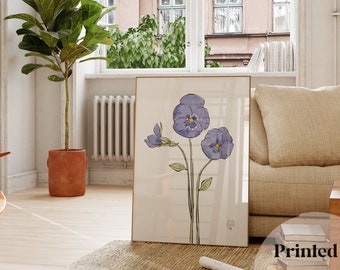 May include: A framed watercolor painting of three purple pansies on a white background. The painting is hanging on a white wall in a living room setting.