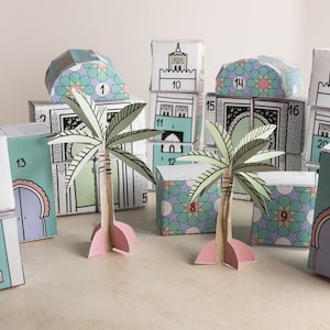 Può includere: Un set di edifici in carta colorati con i numeri da 1 a 22, con una moschea, palme e motivi geometrici. Gli edifici sono impilati uno sopra l'altro, creando una città in miniatura.