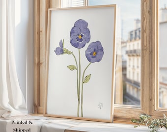 May include: A framed print of a watercolor painting of three purple pansies with yellow centers. The pansies are on a white background with a light green stem and leaves.