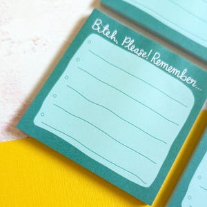 May include: A teal sticky note with the text "Bitch, Please! Remember..." in white script. The note has a light blue interior with horizontal lines and small circles along the left edge. The note is on a yellow surface.