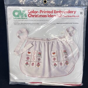 May include: A packaged Christmas Idea Kit featuring a white apron with red trim and embroidered floral and letter designs. The kit includes embroidery thread, needle, and instructions. The package reads "Color-Printed Embroidery Christmas Idea Kit."