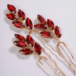 May include: Three gold hair clips with red crystal leaves. Each clip has a wavy, gold wire design.