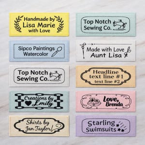 May include: A collection of twelve rectangular fabric labels in various pastel colors including yellow, light blue, white, beige, pink, and lavender. Each label features black printed text and graphics, such as sewing machines, hearts, and floral motifs.