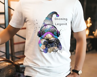 May include: White t-shirt with a graphic of a gnome wearing a headset and holding a video game controller. The text "Gnoming Legend" is printed on the shirt.