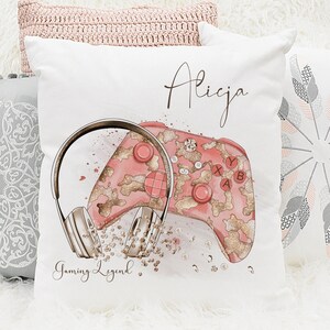 May include: A white pillow with the name "Alicja" printed in black cursive script. The pillow features a pink and gold gaming controller and headphones with a glittery design. The text "Gaming Legend" is printed below the controller and headphones.