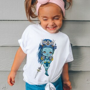 May include: White t-shirt with a blue and green cartoon illustration of a female character with a crown and feathers. The character is holding a spear and has a blue and green outfit.
