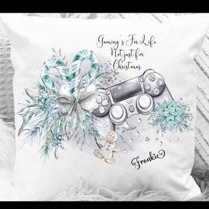 Op de afbeelding: Een wit kussen met een zilver en blauw aquarelontwerp met een videogamecontroller, snoepstokken en een peperkoekman. De tekst "Gaming's For Life Not just for Christmas" en de naam "Frankie" staan op het kussen gedrukt.