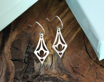 May include: A pair of silver dangle earrings with a geometric design. The earrings are made of a thin metal and have a delicate, intricate pattern.
