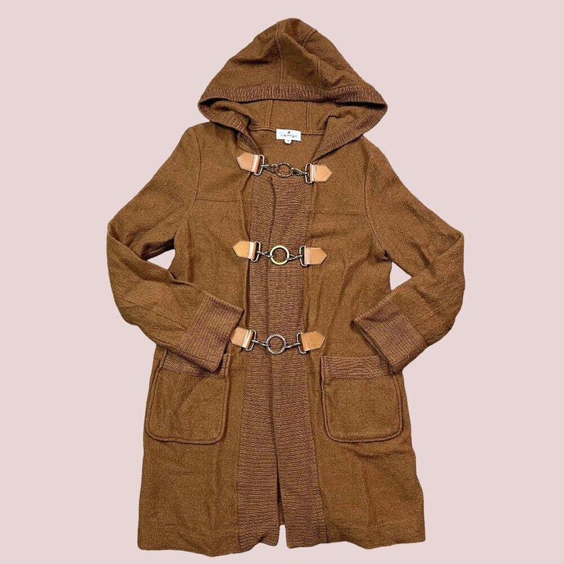 May include: A brown hooded coat with toggle closures and two front pockets. The coat features a ribbed knit trim on the cuffs and a contrasting knit panel down the front. The toggle closures are made of metal and leather.