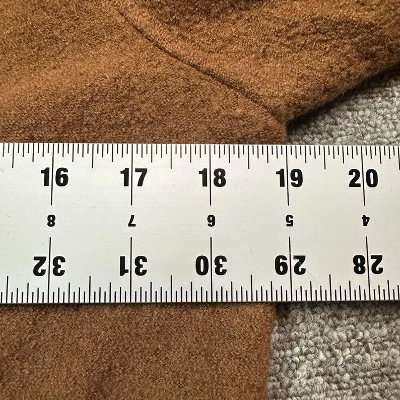 May include: Close-up of a section of brown fabric with a ruler showing measurements in inches. The ruler is white with black markings and numbers, indicating measurements from 16 to 20 inches and 28 to 32 inches.
