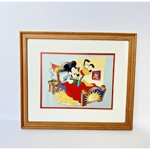Puede incluir: Impresión enmarcada de dibujos animados con Mickey Mouse y Pluto en la cama, leyendo. Mickey está bajo una manta roja, con un libro verde. Pluto está a su lado. La cama tiene un diseño de sol. El marco es de color marrón claro.