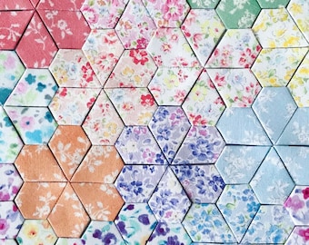 Peut inclure: Une courtepointe faite de pièces de tissu hexagonales dans différents motifs floraux, notamment rose, bleu, vert et violet.