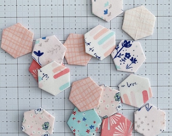 Peut inclure: Un ensemble de 13 patchs en tissu de forme hexagonale avec différents motifs et couleurs, dont le rose, le bleu, le blanc et le gris. Certains patchs comportent du texte, notamment "Just do not" et "In love".
