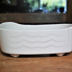 May include: White ceramic bathtub planter with a wavy design and three small feet.