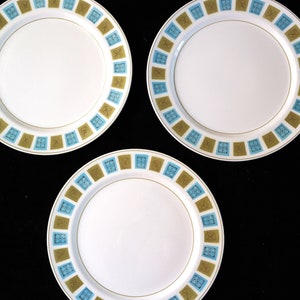 May include: Three white ceramic plates with a blue and gold geometric pattern around the rim.