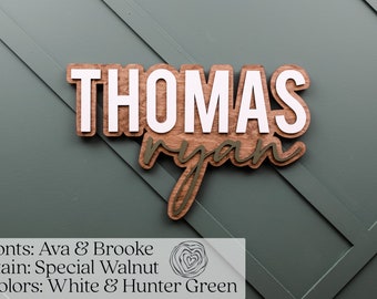May include: Wooden sign with the names "THOMAS" and "ryan" in white and green paint. The sign is stained a dark walnut color. The text "Fonts: Ava & Brooke Stain: Special Walnut Colors: White & Hunter Green" is below the sign.