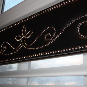May include: A black window valance with a decorative design of silver studs in a swirling pattern.