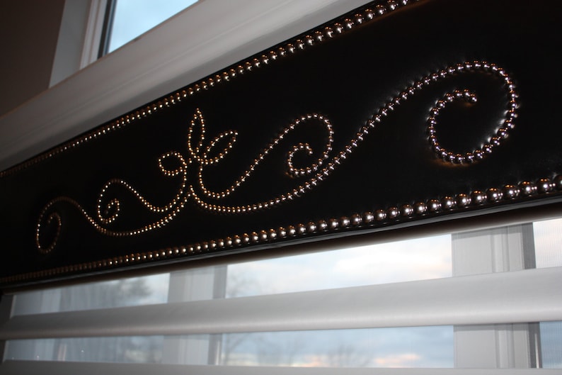 May include: A black window valance with a decorative design of silver studs in a swirling pattern.