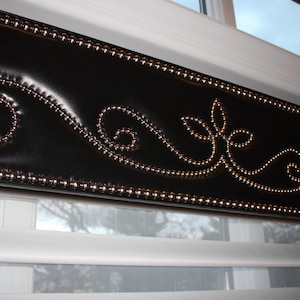 May include: A black window valance with a decorative silver bead trim and a silver beaded floral design.