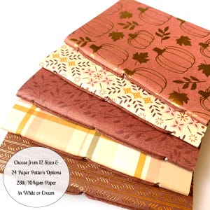 May include: A stack of paper sheets with various fall-themed patterns. The top sheet is a dusty rose color with gold pumpkin and leaf designs. Other sheets feature floral, plaid, and geometric patterns. The text on the image reads: "Choose from 12 Sizes & 24 Paper Pattern Options 28lb/104gsm Paper in White or Cream."
