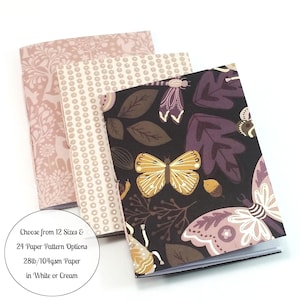 May include: Three notebooks with patterned covers. The front notebook has a black background with a butterfly and leaf design in yellow, purple, and brown. The other two notebooks have pink and cream-colored floral and dot patterns. The text on the image says "Choose from 12 Sizes & 24 Paper Pattern Options 28lb/104gsm Paper in White or Cream."