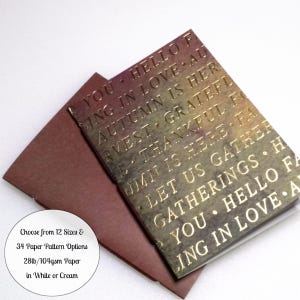 May include: A rectangular card with a gradient background transitioning from deep red to dark brown, featuring gold embossed text including phrases like HELLO FALL, FALLING IN LOVE, AUTUMN IS HERE, HARVEST, THANKFUL, and LET US GATHER, paired with a solid dark red envelope.
