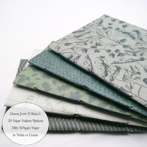 May include: A stack of four paper booklets with stitched spines, featuring various green and gray patterns including botanical leaves, acorns, and stripes. Text on the cover reads: Choose from 12 Sizes & 34 Paper Pattern Options 28lb/104gsm Paper in White or Cream.