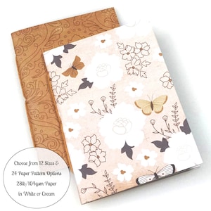 May include: Two small notebooks with different floral patterns. The notebook on the left has a brown paisley pattern. The notebook on the right has a white and brown floral pattern with butterflies. The text on the bottom reads: "Choose from 12 Sizes & 24 Paper Pattern Options 28lb/104gsm Paper in White or Cream"