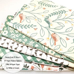 May include: A stack of 12 different patterned paper sheets in green, white, and cream colors. The paper features a floral design with birds. The text on the paper reads: "Choose from 12 Sizes & 24 Paper Pattern Options 28lb/104gsm Paper in White or Cream".
