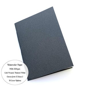 May include: A black watercolor paper pad with a textured cover. The paper is 140lb 300gsm, cold-pressed, and natural white. The image includes text indicating the availability of 12 sizes and 18 cover options.