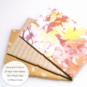 May include: Three stacked rectangular paper sheets featuring autumn-themed designs. The top sheet displays yellow and red maple leaves. The middle sheet has brown text and leaf patterns. The bottom sheet is plain brown with small leaf icons. Text reads: Choose from 12 Sizes & 34 Paper Pattern Options 28lb/104gsm Paper in White or Cream.