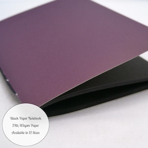 May include: A notebook with a dark purple cover and black paper pages. A circular white label on the cover displays the text: Black Paper Notebook, 24lb/89gsm Paper, Available in 12 Sizes.